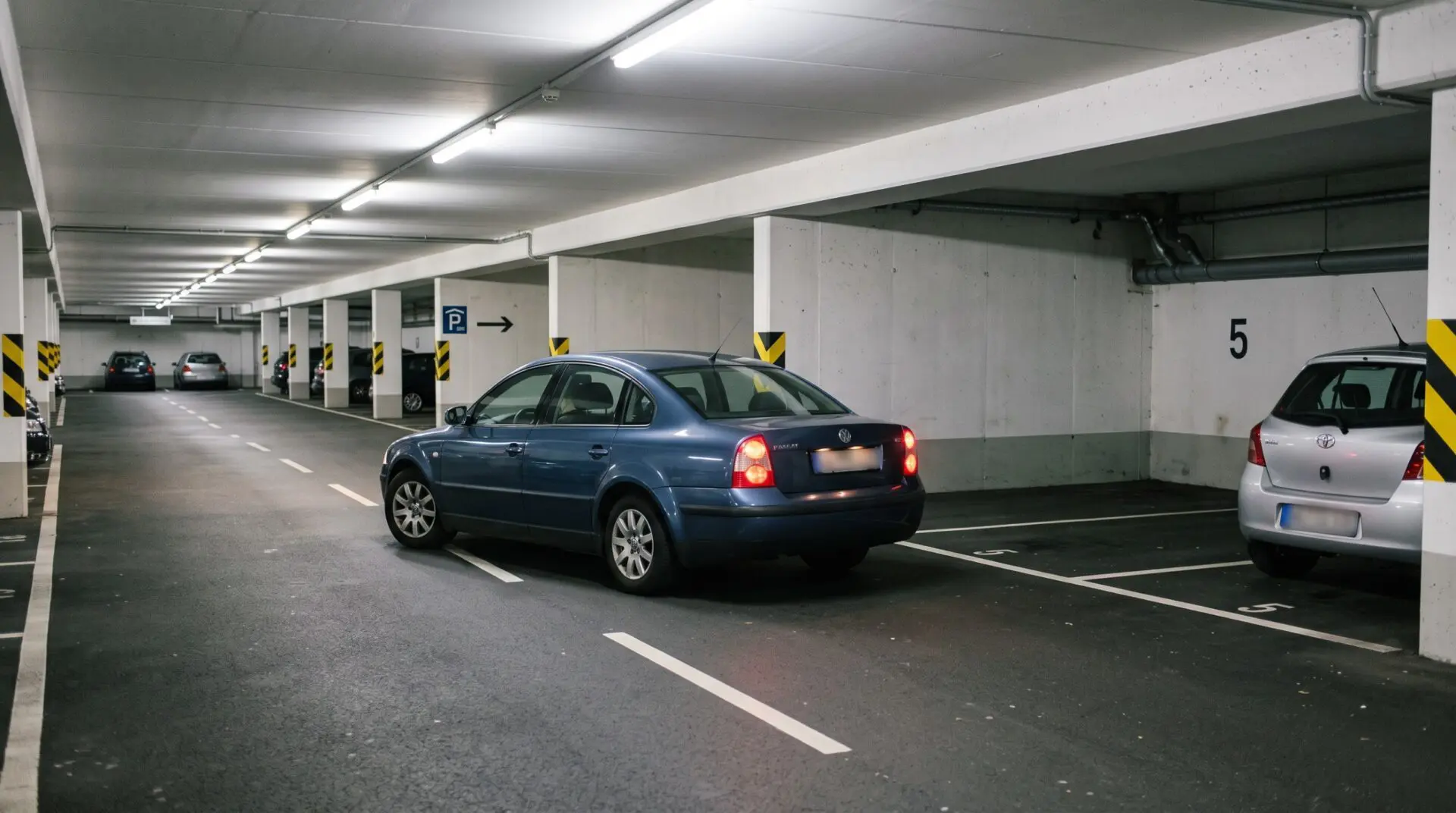 Pkw steht schräg vor Stellplatz 5 in deutscher Tiefgarage, flankiert von Seitenwand und belegtem Platz daneben.