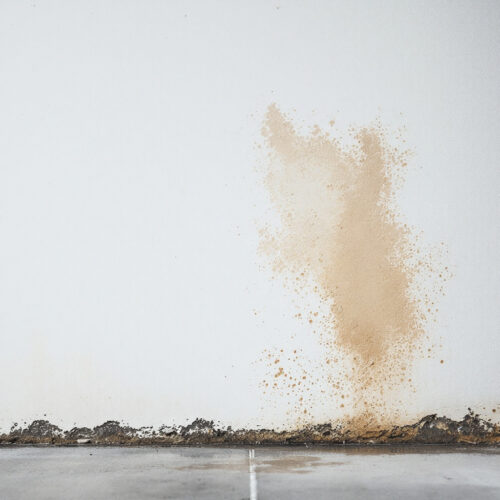 Feuchter Fleck an weißer Kellerwand in Neubau-Reihenhaus, kein sichtbarer Schimmel oder Schäden.