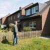 zulassung-berufung-dachausbau Anwohner im Garten schaut zum neuen Dachaufbau am Nachbarhaus mit Schatten über Zaun